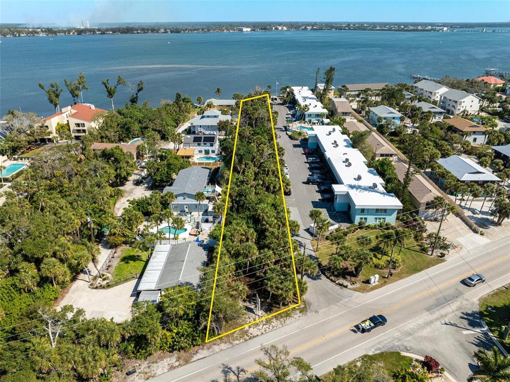 An aerial view shows a vacant, tree-covered lot outlined in yellow next to a road — 5065 N BEACH ROAD, ENGLEWOOD, FL