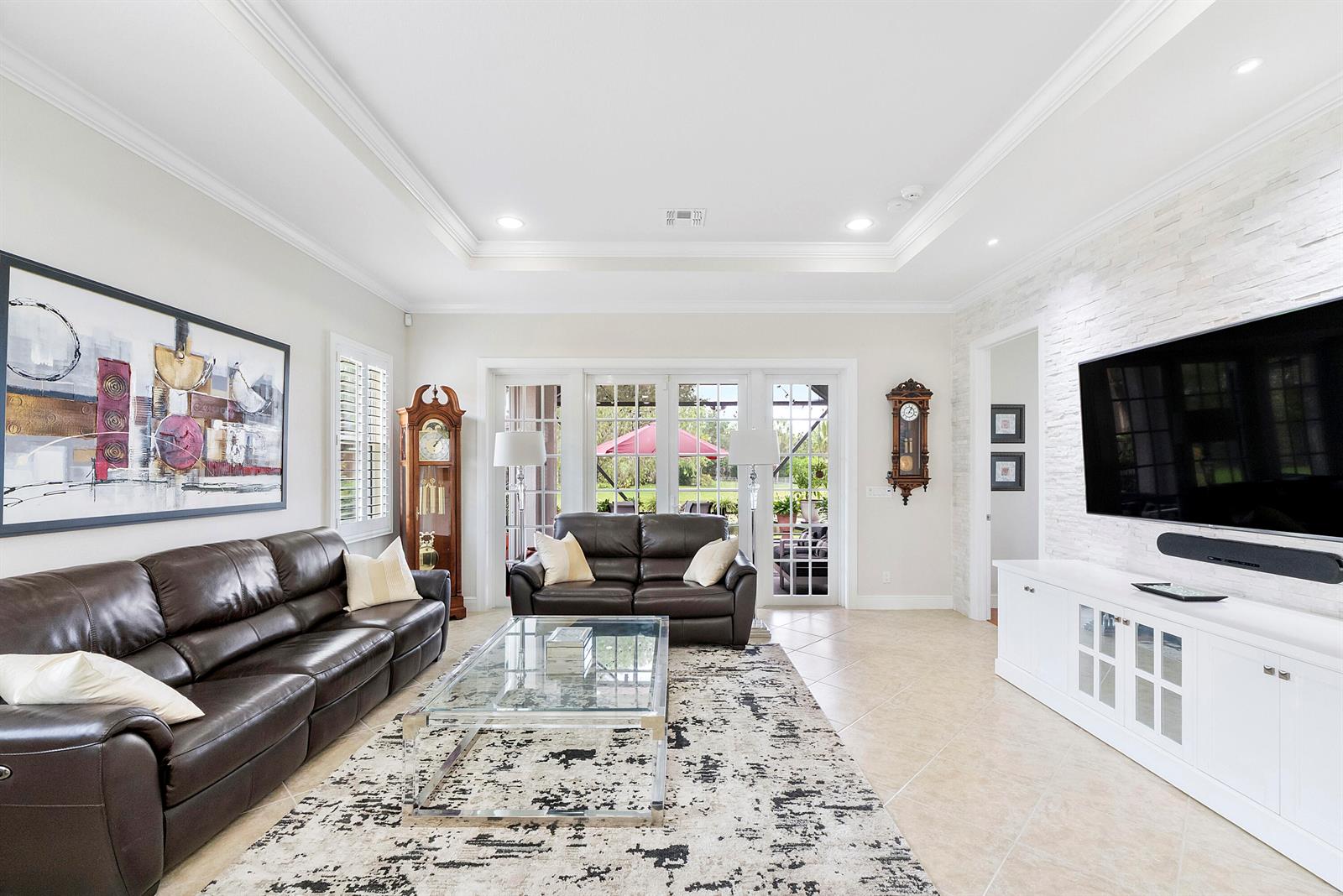 A living room features two leather sofas, a glass coffee table, and a wall-mounted television — 8240 NW 120th Way, Parkland FL 33076, PARKLAND, FL