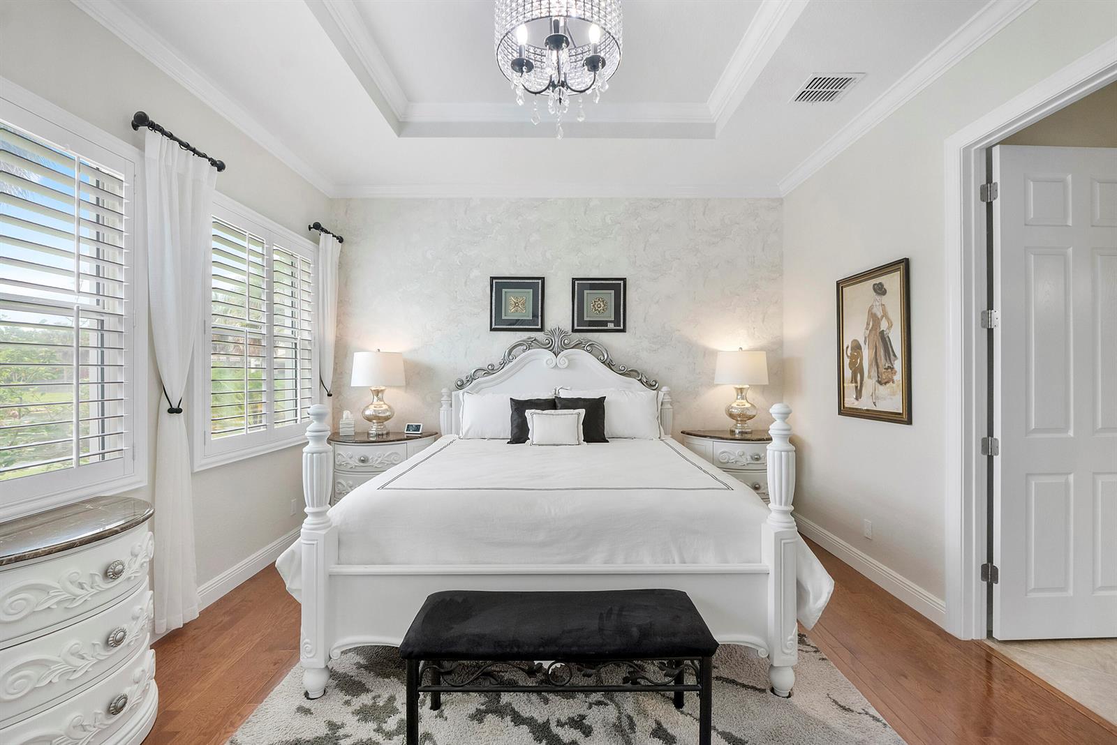 A bedroom features a white four-poster bed, a crystal chandelier, and hardwood floors — 8240 NW 120th Way, Parkland FL 33076, PARKLAND, FL