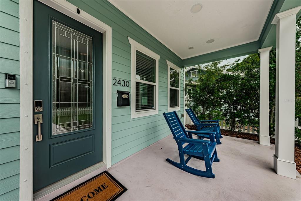 A covered front porch features light green siding, a dark teal door, and two blue rockers — 2430 6TH AVENUE N, ST PETERSBURG, FL