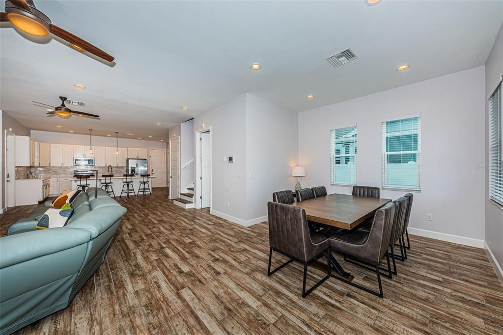 An open-concept living and dining area features wood-look tile flooring and a modern kitchen — 2430 6TH AVENUE N, ST PETERSBURG, FL
