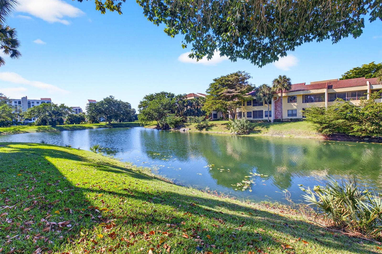 A grassy lawn slopes down to a pond in front of multi-story apartment buildings — 7484 La Paz Boulevard # 103, Boca Raton FL 33433, BOCA RATON, FL