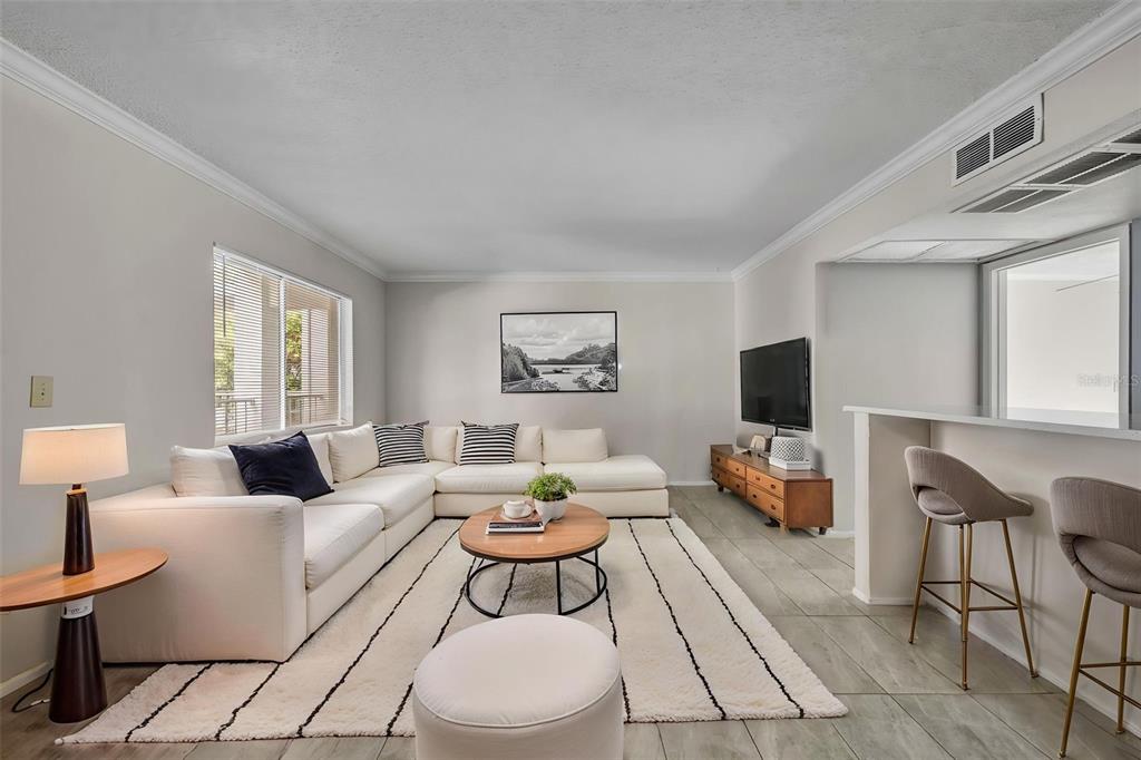 A bright living room features a white sectional sofa, a round coffee table, and tile flooring — 145 OYSTER BAY CIRCLE UNIT 240, ALTAMONTE SPRINGS, FL