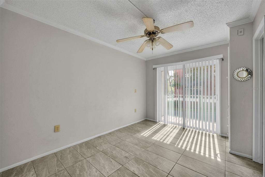 An empty room with light-colored tile flooring, a ceiling fan, and sliding glass patio doors — 145 OYSTER BAY CIRCLE UNIT 240, ALTAMONTE SPRINGS, FL