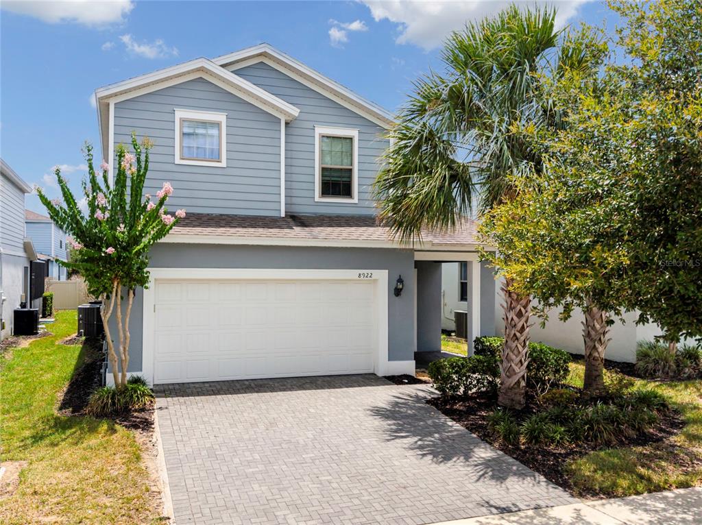 A two-story house with light blue siding, a white garage door, and a paved driveway — 8922 ZURICH LANE, KISSIMMEE, FL
