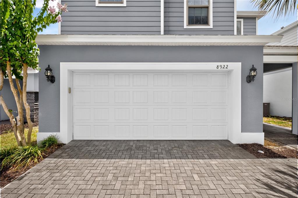 A white garage door is centered on the gray exterior of a two-story house — 8922 ZURICH LANE, KISSIMMEE, FL
