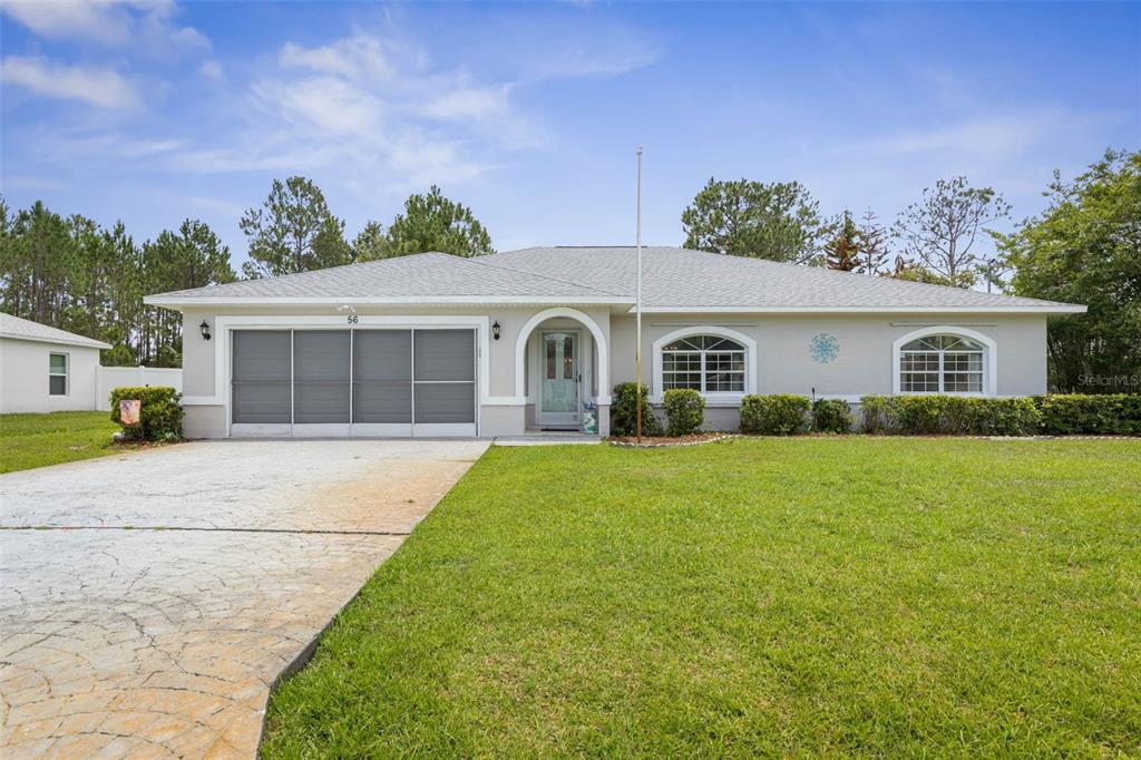 A single-story house with a gray roof, light-colored stucco exterior, and a concrete driveway — 56 PRITCHARD DRIVE, PALM COAST, FL