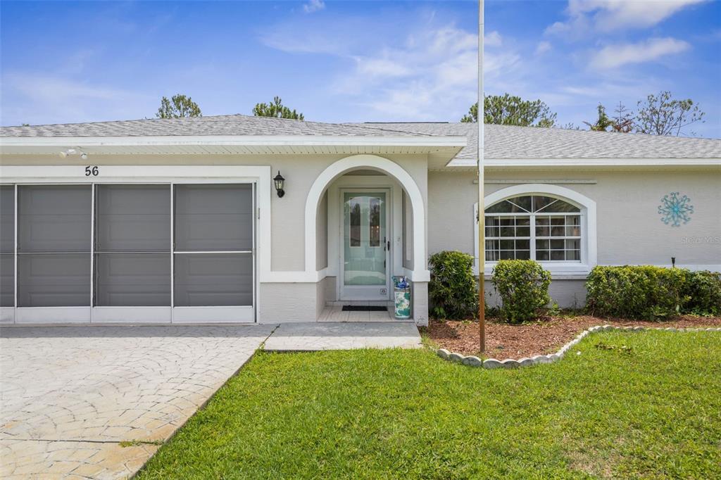 The exterior of a single-story home features a screened garage, arched entryway, and arched window — 56 PRITCHARD DRIVE, PALM COAST, FL