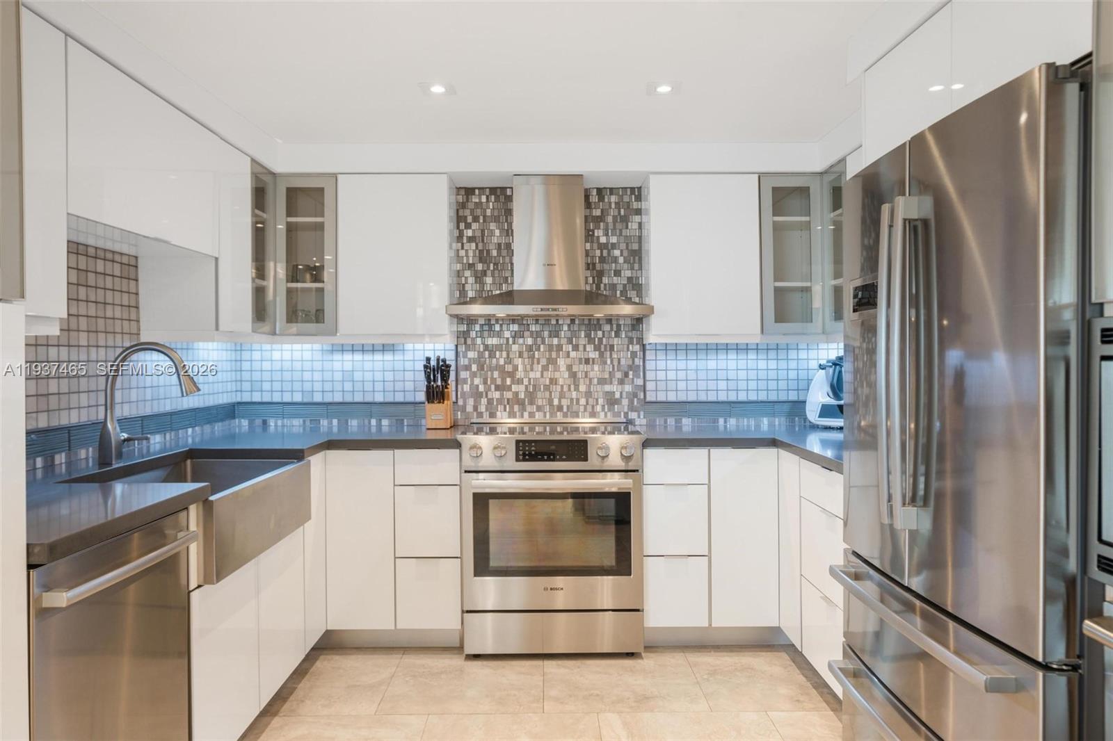 A modern kitchen features white cabinets, stainless steel appliances, and a mosaic tile backsplash — 5225 Collins Ave # 1221, Miami Beach FL 33140, MIAMI BEACH, FL