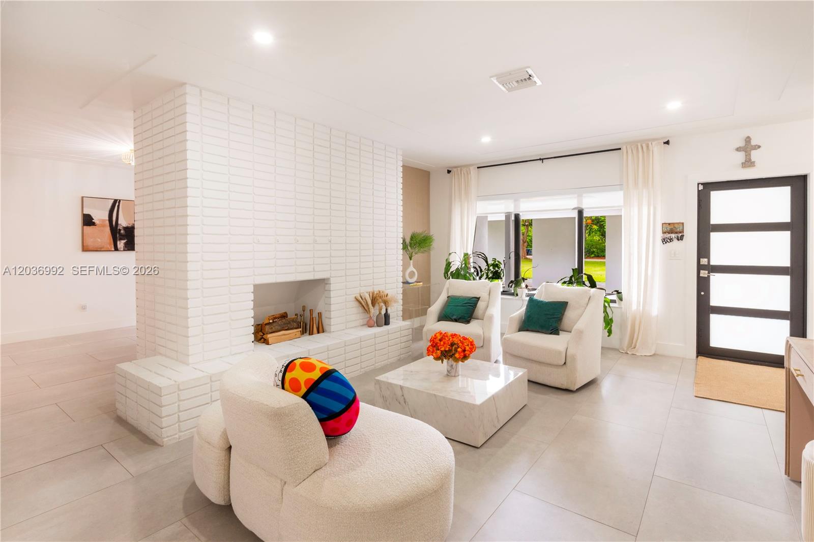 A living room features a white brick fireplace, light tile flooring, and modern seating — 7970 SW 122nd St, Pinecrest FL 33156, PINECREST, FL
