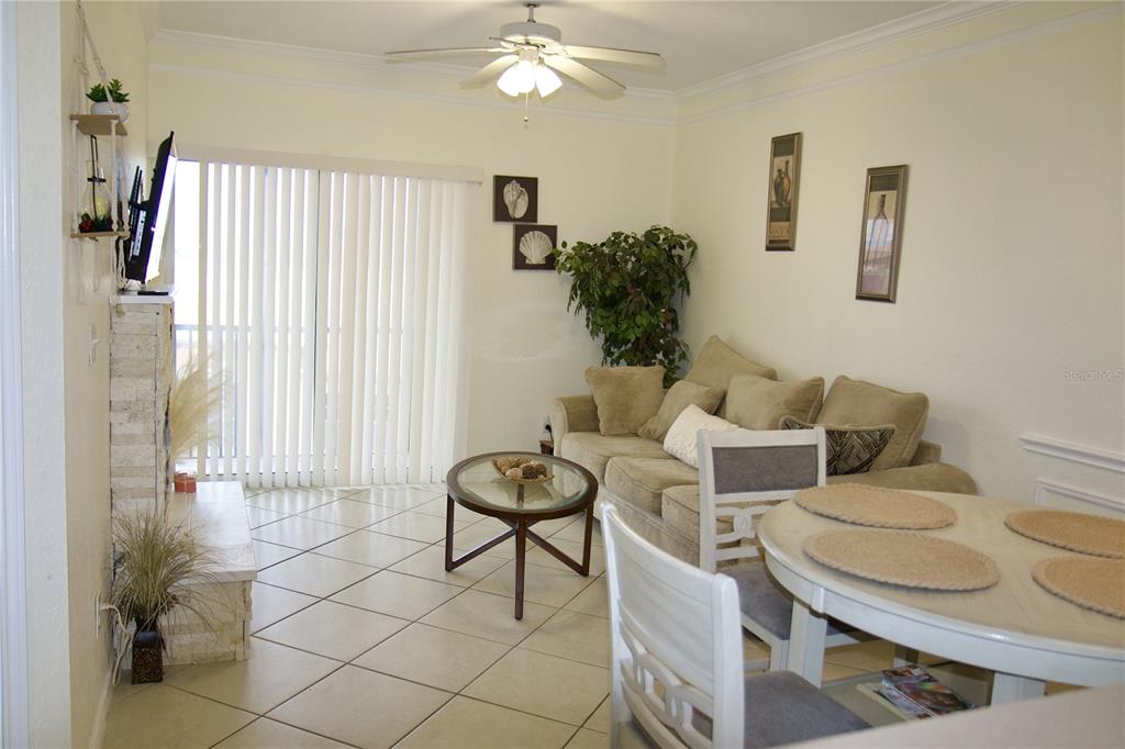 A living room features tile flooring, a beige sofa, a glass coffee table, and a dining set — 4323 BAYSIDE VILLAGE DRIVE UNIT 306, TAMPA, FL