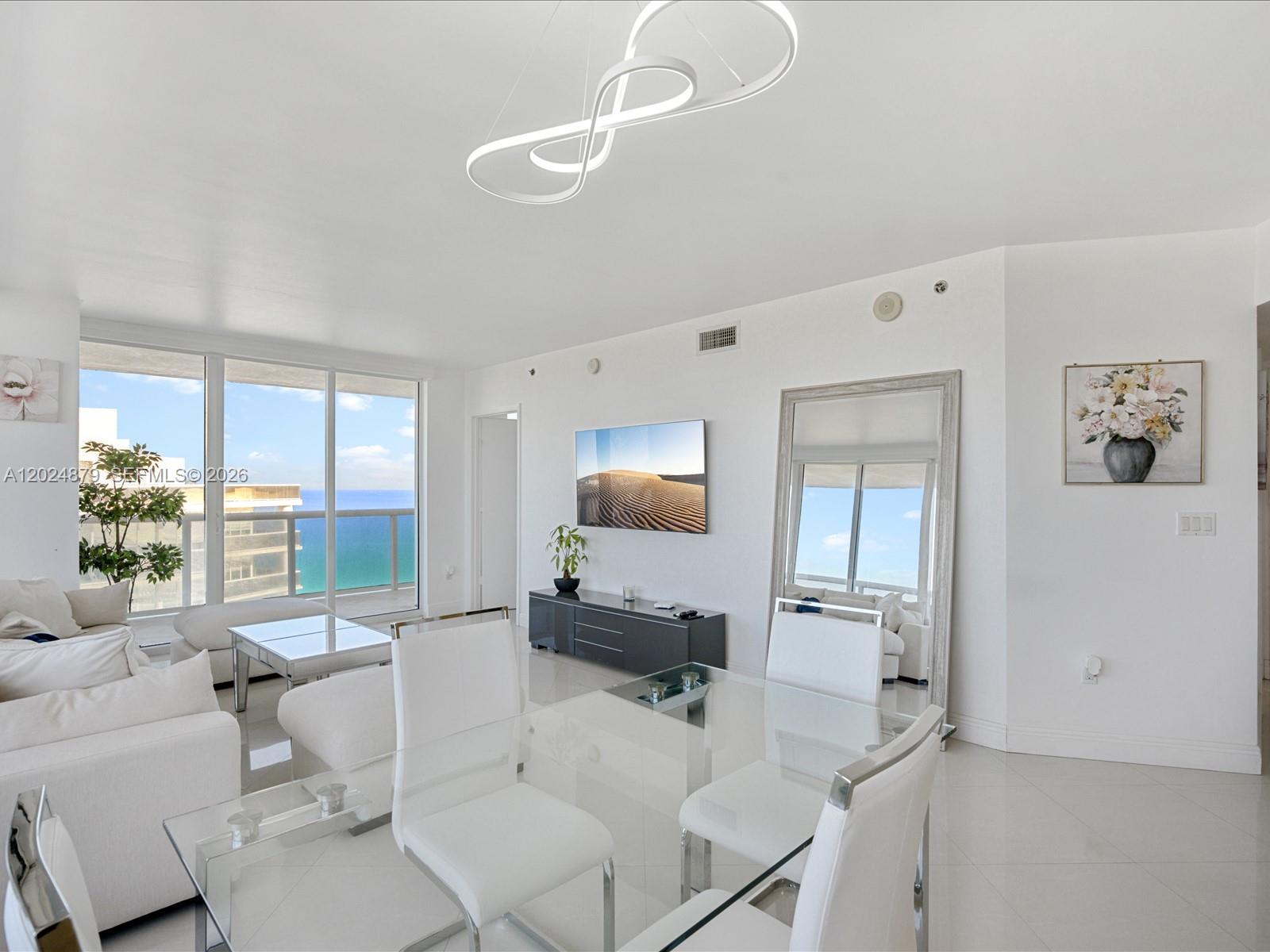 A bright, modern living and dining area features white furniture, a glass table, and ocean views — 1830 S Ocean Dr # 4508, Hallandale Beach FL 33009, HALLANDALE BEACH, FL