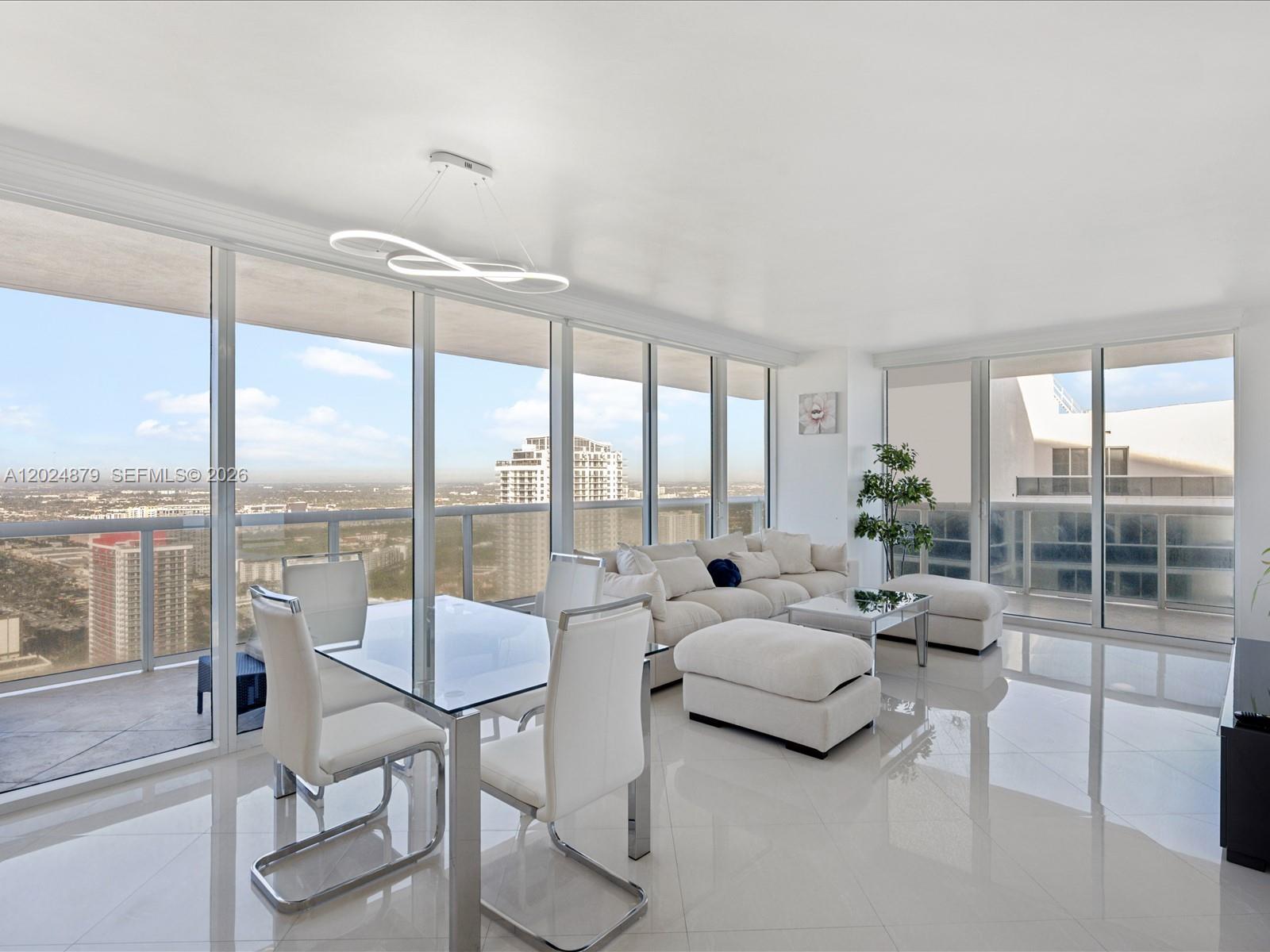 A bright living and dining area features white furniture, glass tables, and floor-to-ceiling windows — 1830 S Ocean Dr # 4508, Hallandale Beach FL 33009, HALLANDALE BEACH, FL