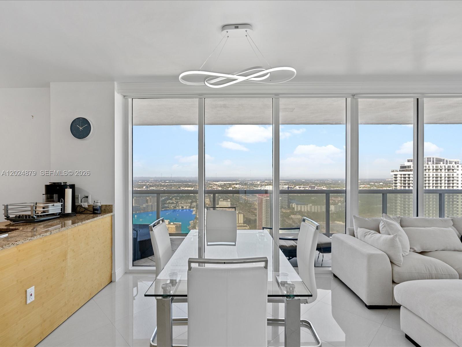 A dining area with a glass table and white chairs sits before floor-to-ceiling windows — 1830 S Ocean Dr # 4508, Hallandale Beach FL 33009, HALLANDALE BEACH, FL