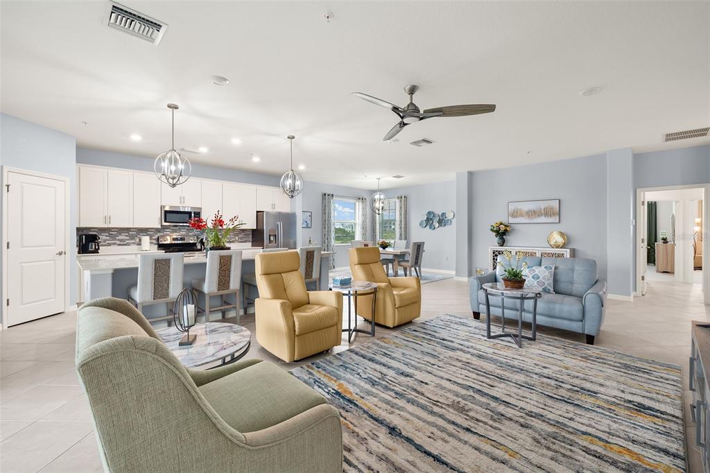 An open-concept living room and kitchen featuring light blue walls, tile floors, and modern furniture — 14150 POPPY FIELD LOOP UNIT 4322, PUNTA GORDA, FL
