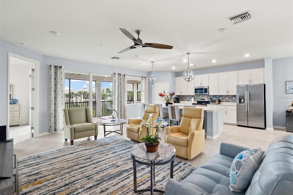 An open-concept living room and kitchen featuring light-colored cabinetry, tile floors, and a balcony view — 14150 POPPY FIELD LOOP UNIT 4322, PUNTA GORDA, FL