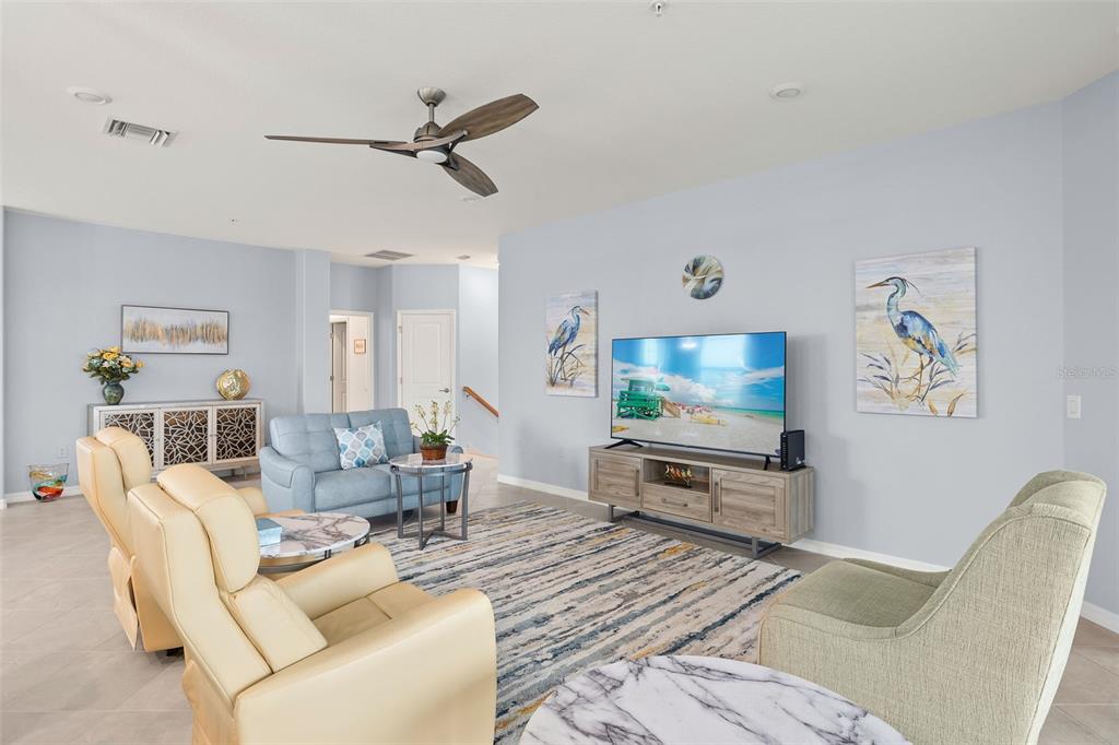 A living room features light blue walls, a ceiling fan, and a television on a console — 14150 POPPY FIELD LOOP UNIT 4322, PUNTA GORDA, FL
