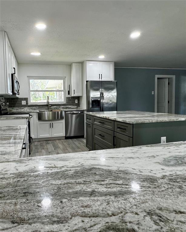 A kitchen features white upper cabinets, dark gray island cabinetry, and light-colored stone countertops — 34817 ORCHID PARKWAY, DADE CITY, FL