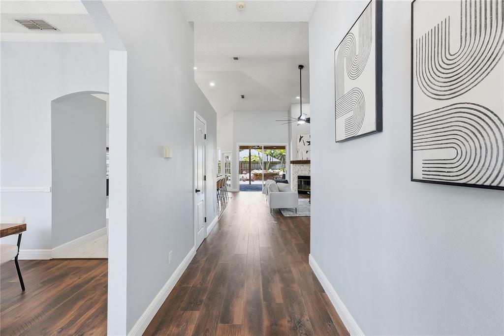 A hallway with wood-look flooring leads to a living area with a view of a pool — 13000 CRYSTAL COVE DRIVE, ORLANDO, FL