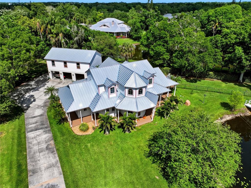 An aerial view shows a multi-story house with a metal roof and detached garage — 13227 110TH AVENUE, LARGO, FL
