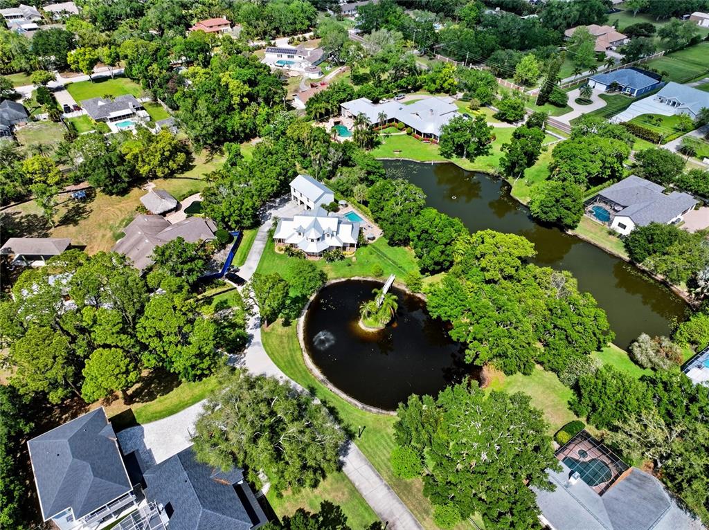 An aerial view shows a residential property with a house, a circular pond, and trees — 13227 110TH AVENUE, LARGO, FL