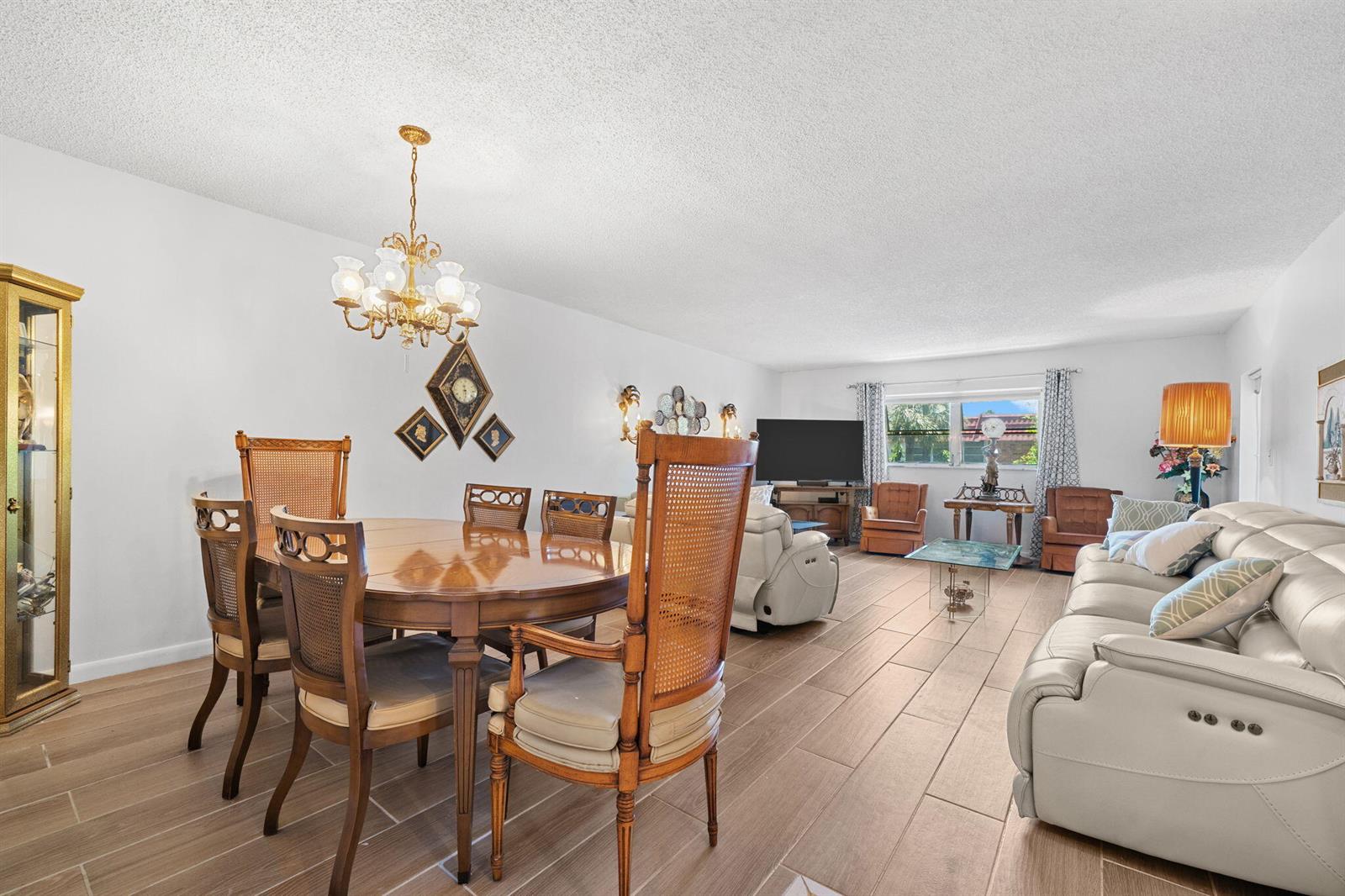 An open-concept living and dining area features light wood-look tile flooring and white walls — 2271 NW 48th Terrace # 207, Lauderhill FL 33313, LAUDERHILL, FL
