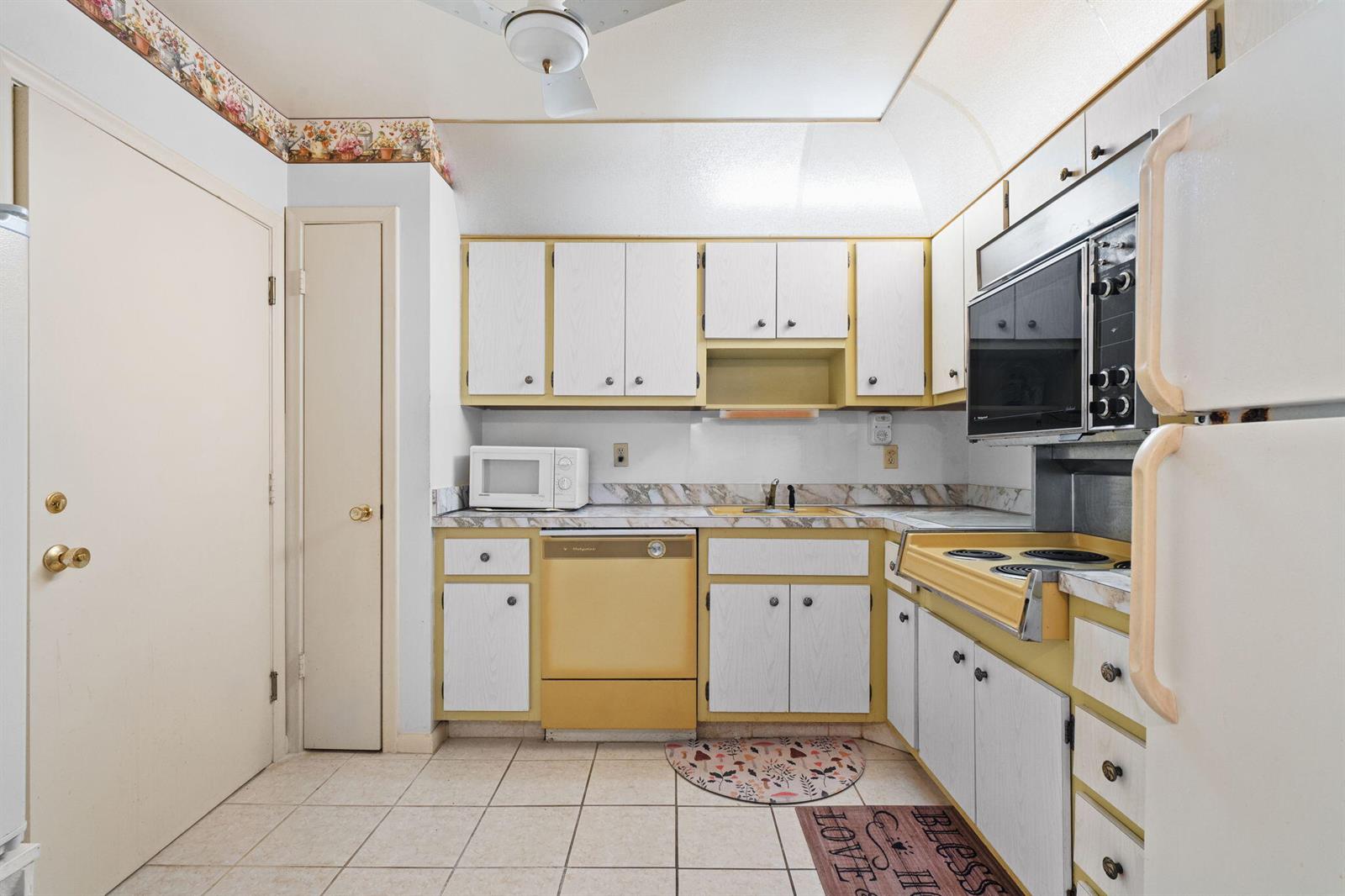 A kitchen features yellow appliances, white cabinets, tiled floors, and a floral wallpaper border — 2271 NW 48th Terrace # 207, Lauderhill FL 33313, LAUDERHILL, FL