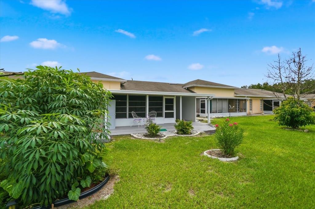 The exterior of a single-story house features a screened-in patio and a grassy backyard — 2237 CLUB CIRCLE, LAKE WALES, FL