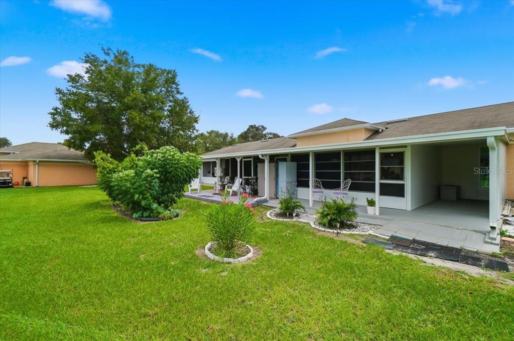 A backyard view of a house with a covered patio, lawn, and landscaping — 2237 CLUB CIRCLE, LAKE WALES, FL