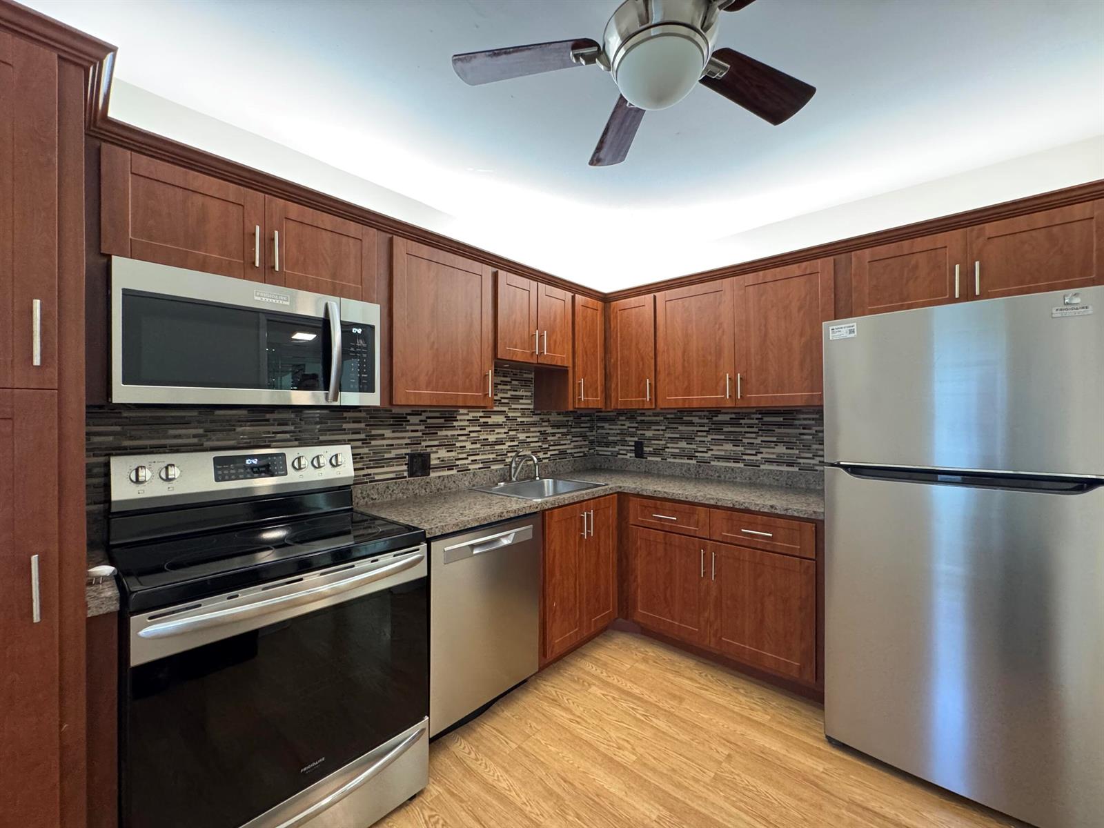 A kitchen features wood cabinets, stainless steel appliances, granite countertops, and a tiled backsplash — 2650 S Course Drive # 407, Pompano Beach FL 33069, POMPANO BEACH, FL