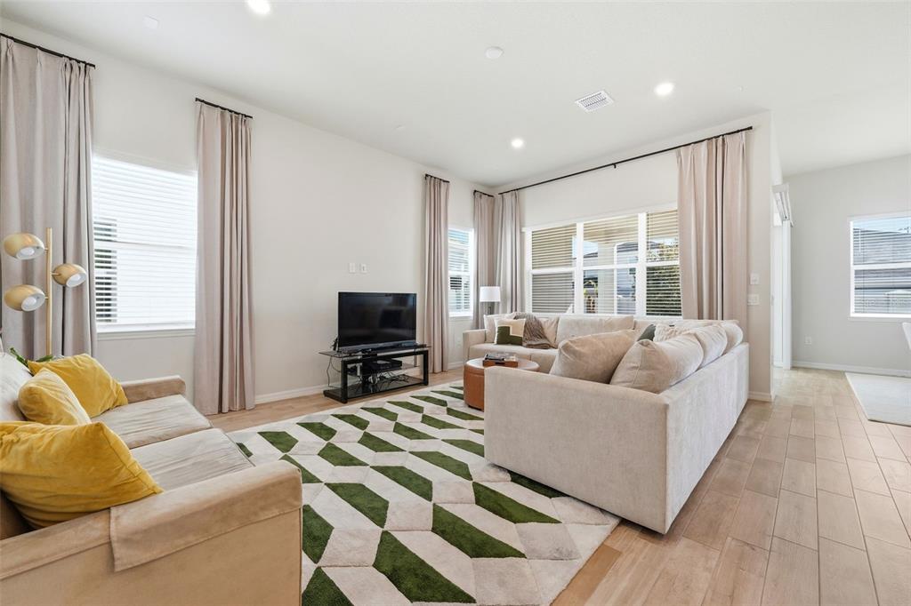 A living room features a sectional sofa, a patterned rug, and a television on a stand — 10325 PARKVIEW RESERVE LANE, ORLANDO, FL