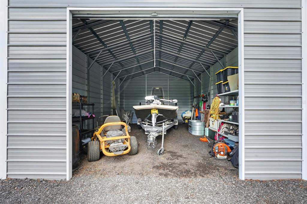 A metal storage shed contains a boat on a trailer and a yellow riding lawnmower — 4825 PECAN AVENUE, BUNNELL, FL
