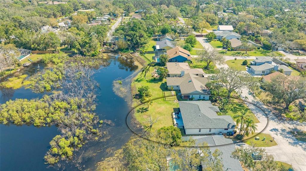 An aerial view of a suburban house with a gray roof situated beside a pond — 3033 GRAFTON STREET, SARASOTA, FL