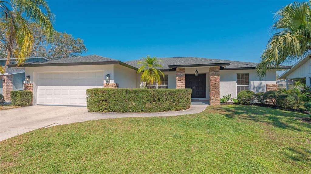 A single-story house with a white exterior, stone accents, a two-car garage, and a lawn — 3033 GRAFTON STREET, SARASOTA, FL