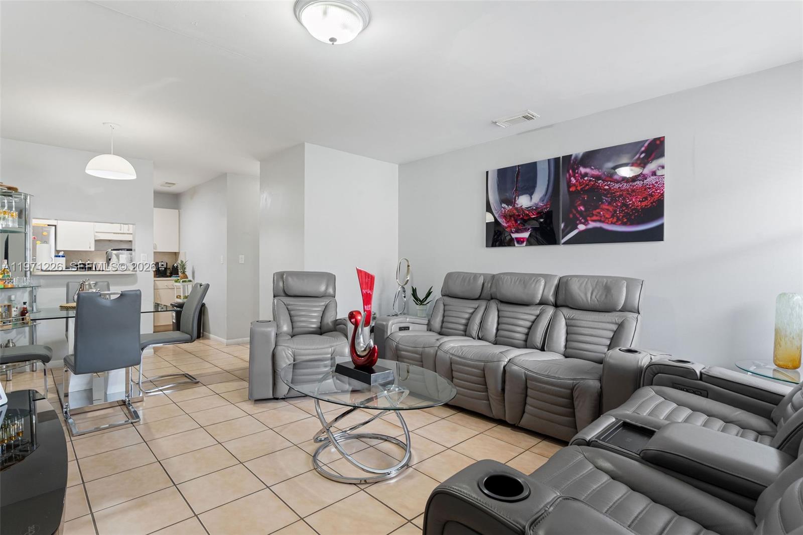 A living room features gray leather reclining furniture, a glass coffee table, and tile flooring — 7111 SW 129th Ave # 6, Miami FL 33183, MIAMI, FL