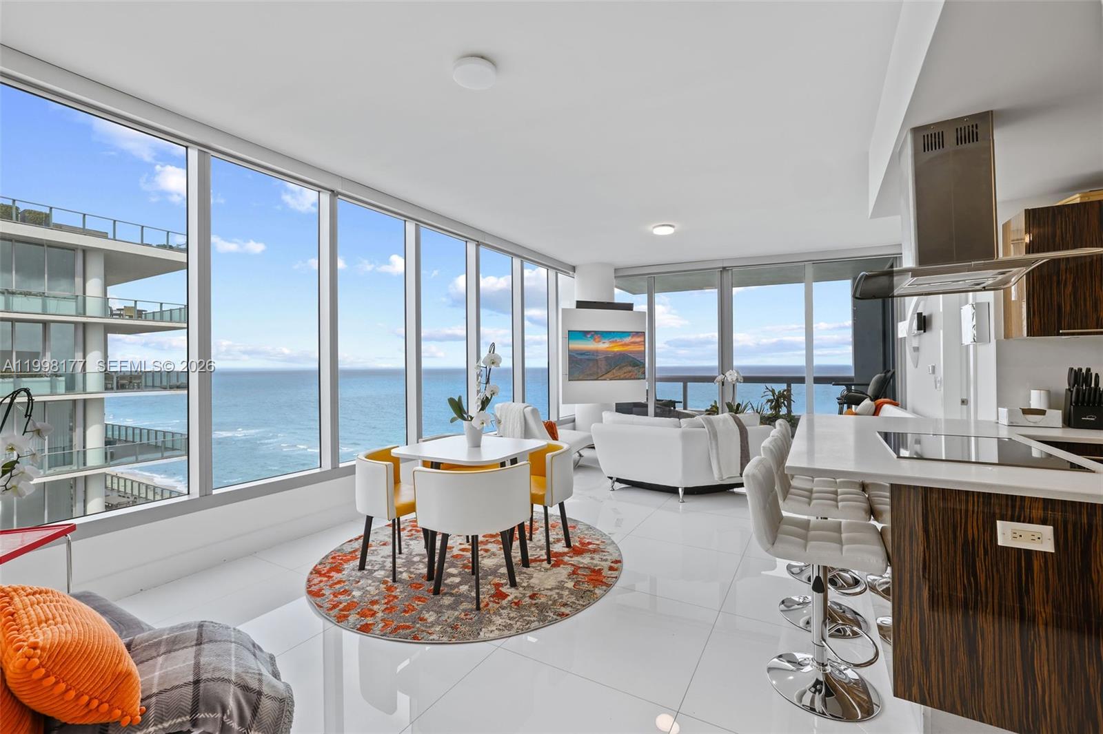 An open-concept living and dining area features floor-to-ceiling windows with ocean views and tile flooring — 6899 Collins Ave # 1905, Miami Beach FL 33141, MIAMI BEACH, FL