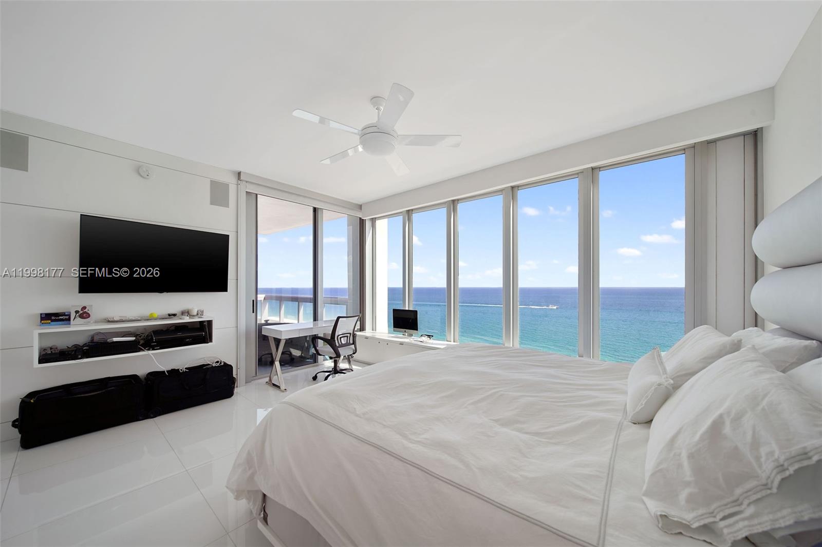 A modern bedroom features white tile floors, a large bed, and floor-to-ceiling ocean views — 6899 Collins Ave # 1905, Miami Beach FL 33141, MIAMI BEACH, FL