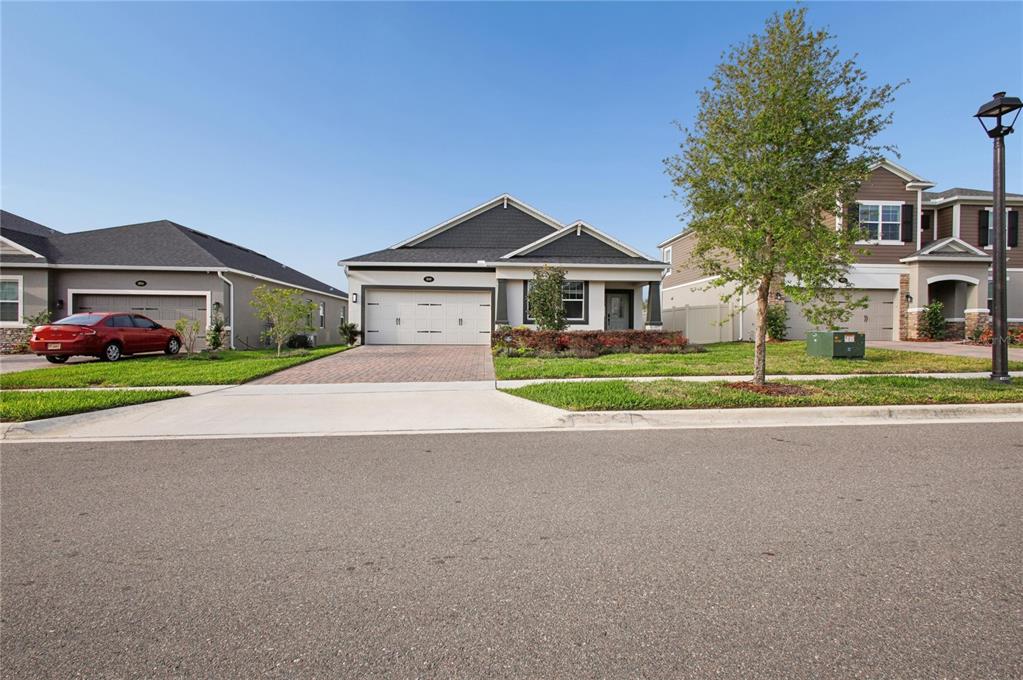 A single-story suburban house with a two-car garage and a paved driveway — 900 POINTE EMERSON BOULEVARD, APOPKA, FL