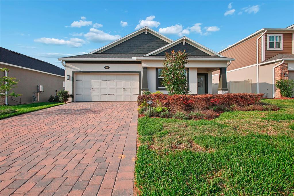 A single-story house with a brick paver driveway, two-car garage, and a front garden — 900 POINTE EMERSON BOULEVARD, APOPKA, FL