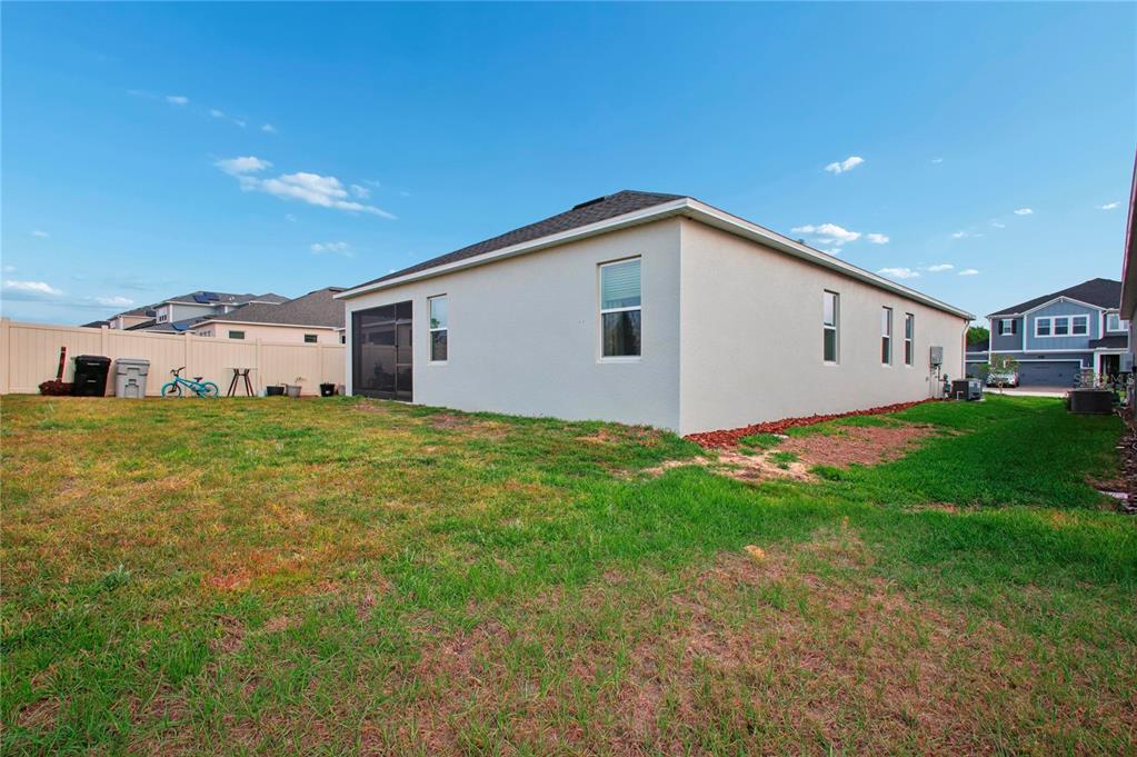 The exterior of a single-story house with a fenced backyard and a screened-in patio — 900 POINTE EMERSON BOULEVARD, APOPKA, FL