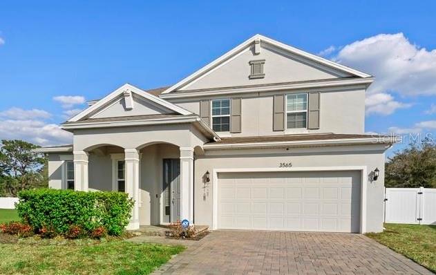 A two-story suburban house with a beige stucco exterior, a two-car garage, and a driveway — 3565 FERNANDA DRIVE, DELTONA, FL