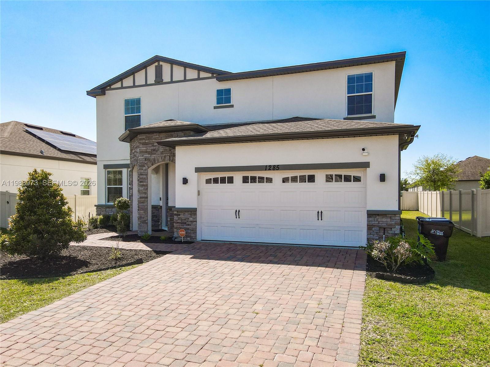 A two-story house features a white stucco exterior, stone accents, and a paved driveway — 1285 Hilltop Place, Saint Cloud FL 34772, SAINT CLOUD, FL