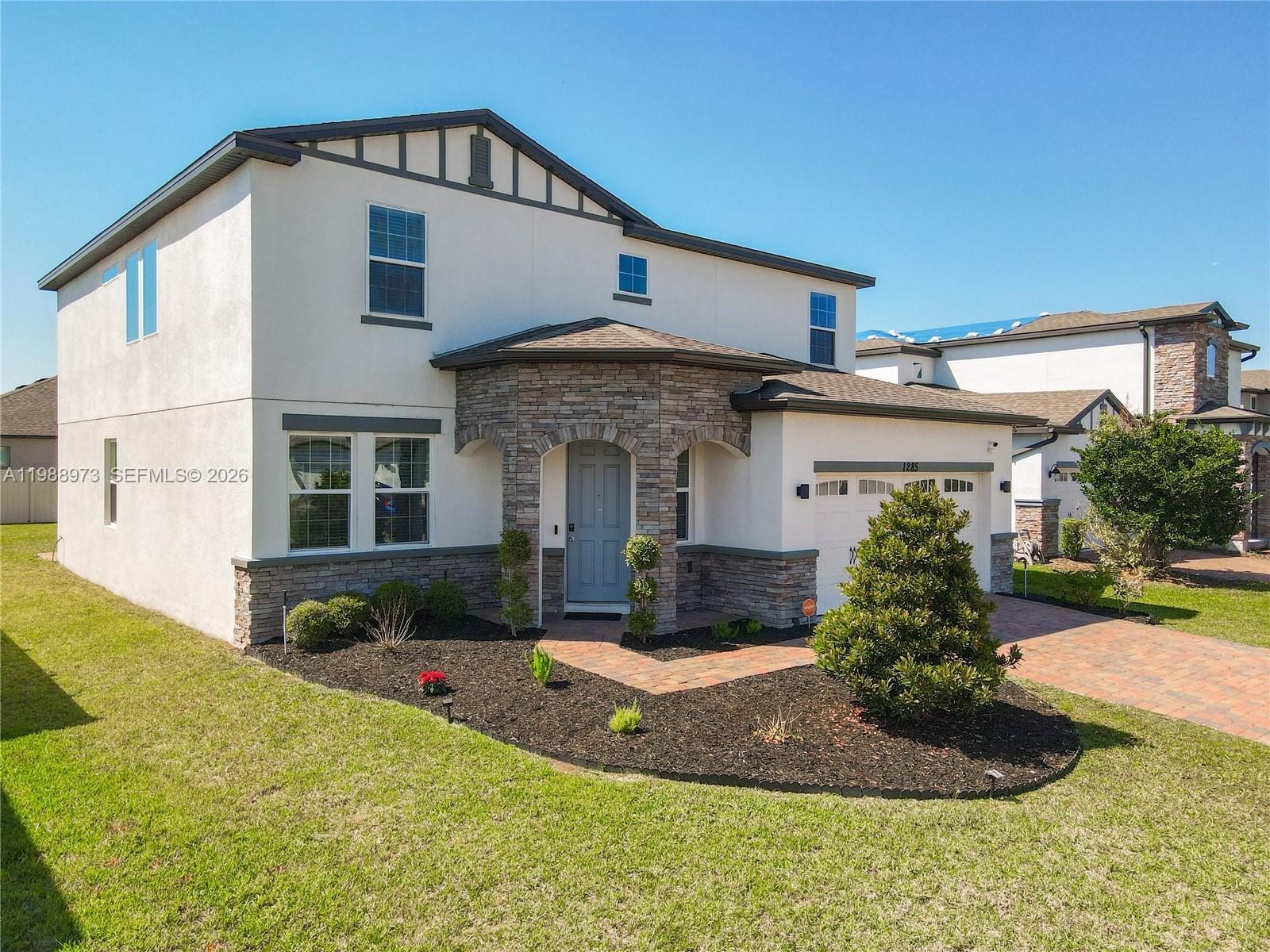 A two-story house with a stone-accented entryway, a paved driveway, and a landscaped front yard — 1285 Hilltop Place, Saint Cloud FL 34772, SAINT CLOUD, FL