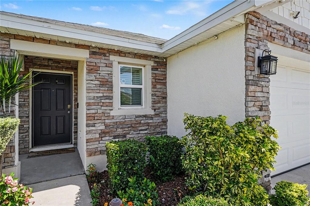 The exterior of a house features a dark front door, stone veneer, and landscaping — 11453 STONE PINE STREET, RIVERVIEW, FL