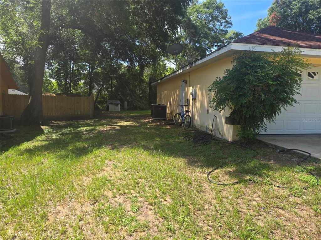 The side yard of a house features a garage, a bicycle, and a wooden fence — 31 PINE CIRCLE, OCALA, FL