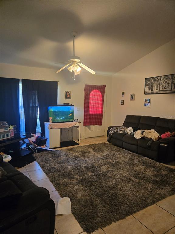 A living room features tile flooring, a large area rug, a ceiling fan, and furniture — 31 PINE CIRCLE, OCALA, FL