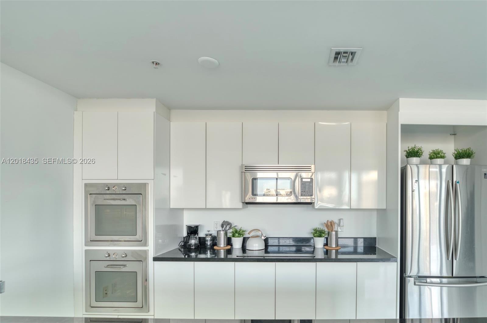 A modern kitchen features white cabinets, stainless steel appliances, and black countertops — 92 SW 3rd St # 5203, Miami FL 33130, MIAMI, FL