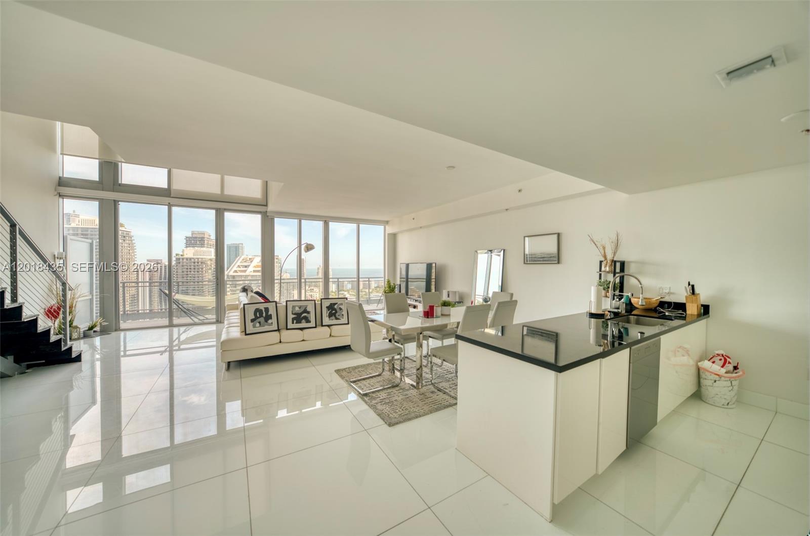 A modern open-concept living and dining area features white tile floors and floor-to-ceiling windows — 92 SW 3rd St # 5203, Miami FL 33130, MIAMI, FL