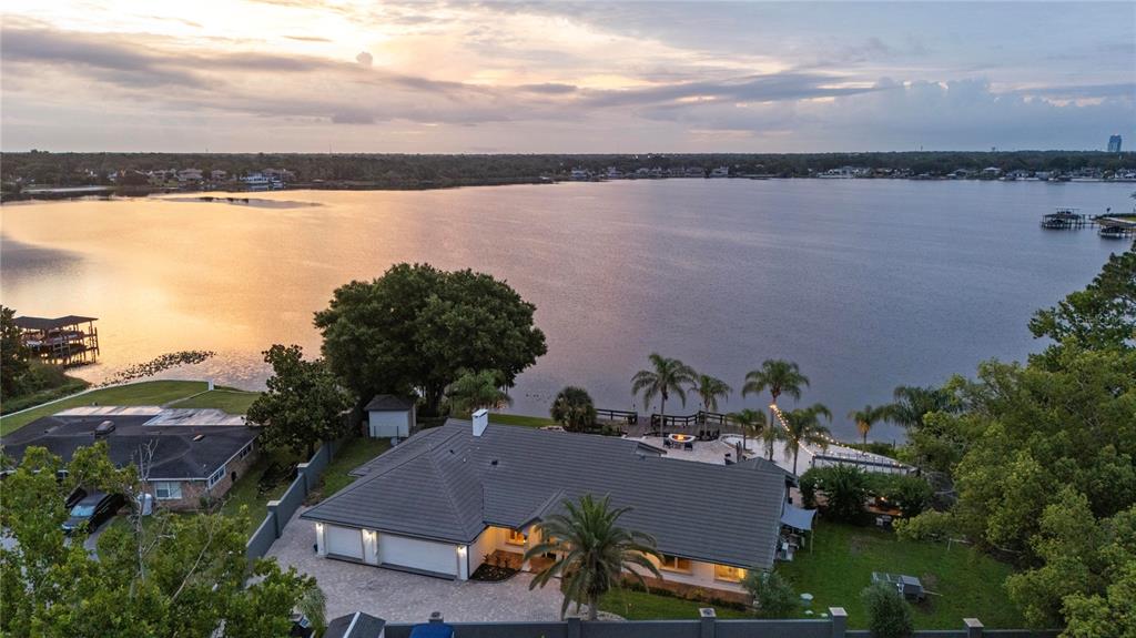 An aerial view of a waterfront house with a paved driveway and a backyard patio — 2201 COVE COURT, LONGWOOD, FL