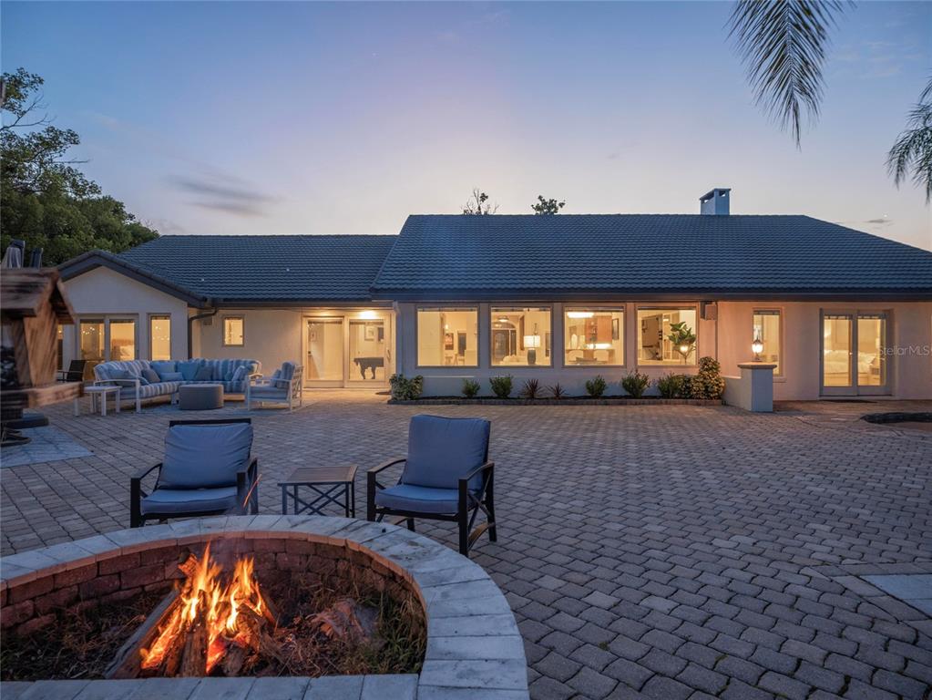A backyard patio features a stone fire pit, outdoor seating, and a single-story house exterior — 2201 COVE COURT, LONGWOOD, FL